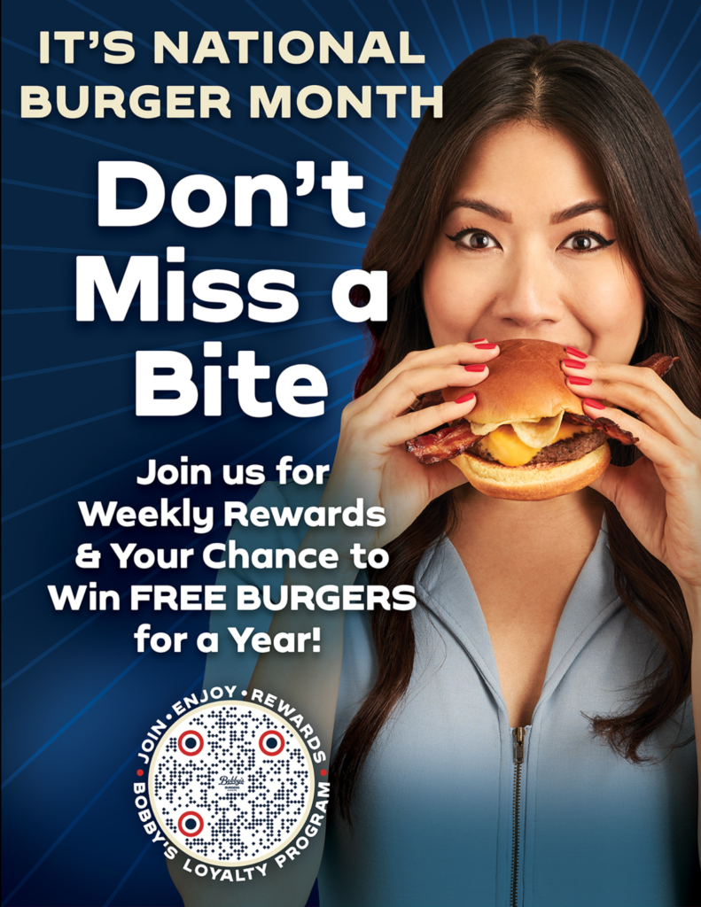 Woman eats a large burger on a blue promo background reading 'Don't Miss a Bite' for National Burger Month.